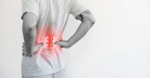man holding his back in pain while the affected area is highlighted in red